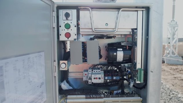 Switchboard with mounted electrical equipment in the territory of a power substation. The smooth movement of the camera from top to bottom.