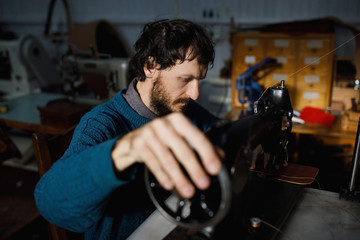 Fototapeta na wymiar A leather craftsman works in a workshop. 