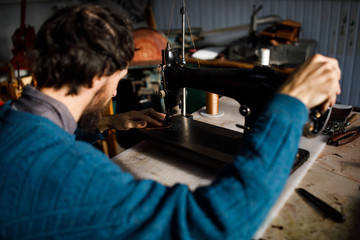 A leather craftsman works in a workshop. 