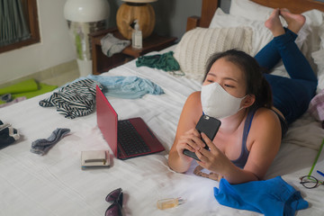 hand phone addiction in times of covid-19 - young bored and messy Asian girl on chaotic bed as...