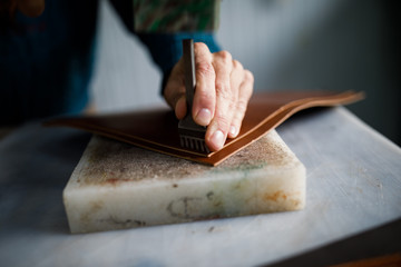 A leather craftsman works in a workshop. 