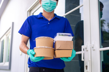 Deliveryman wears a mask and gloves, delivery food to the home of the online buyer. stay at home...