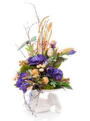 Decorative Easter composition. A bunny holds a composition of flowers.