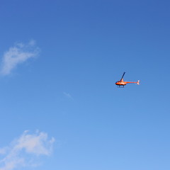 Fototapeta na wymiar Private small orange helicopter on a background of blue sky
