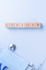 COVID-19 word wooden cube with mask, medical equipment, world disease pandemic infection and prevention concept, top view, flat lay, overhead design