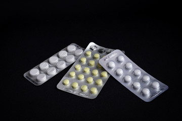 Top view of white tablets in blister isolated on dark black background