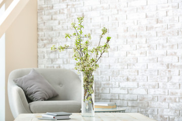 Vase with beautiful blooming branches on table in room