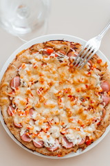 One glass of white wine and pizza with salami, mushrooms, pepper and cheese.
