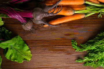 organic beetroots and carrots on rustic wooden background