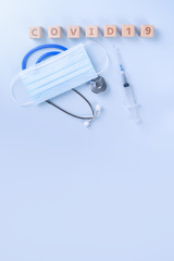 COVID-19 word wooden cube with mask, medical equipment, world disease pandemic infection and prevention concept, top view, flat lay, overhead design