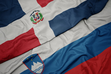 waving colorful flag of slovenia and national flag of dominican republic.