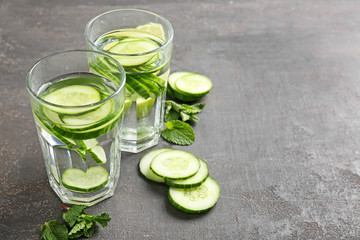 Glasses of infused cucumber water on dark background