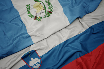 waving colorful flag of slovenia and national flag of guatemala.