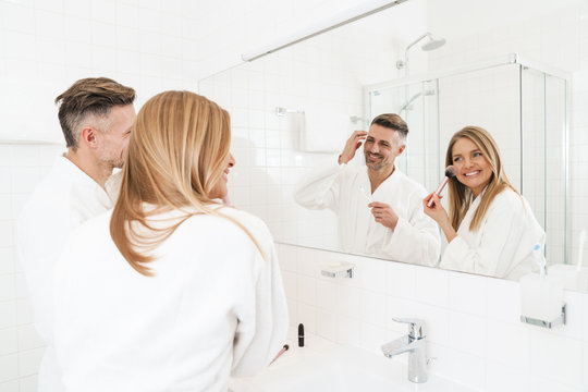 Photo of happy couple smiling and looking at mirror in bathroom