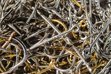 A lot of silver and gold fishing hooks. Fishing hook background.