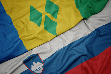 waving colorful flag of slovenia and national flag of saint vincent and the grenadines.
