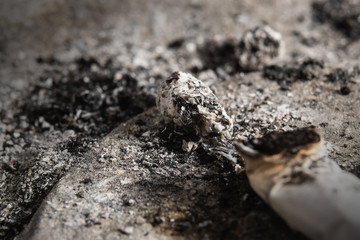 FOCUS ON THE ASHES. Smoked cigarette on the ashtray with ashes around. Cigarette butt and ashes background.