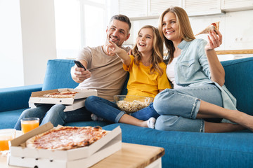 Photo of cheerful family eating popcorn and pizza while watching tv