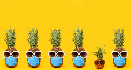 Series of pineapples in sunglasses and medical mask on a yellow background