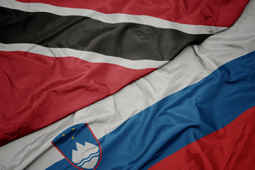 waving colorful flag of slovenia and national flag of trinidad and tobago.