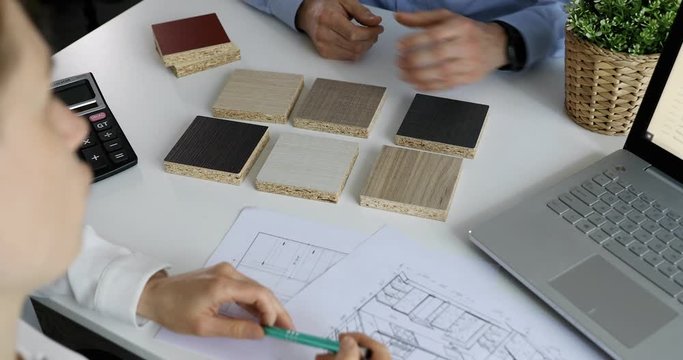 designer and customer choosing kitchen furniture materials from samples at interior design shop