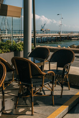 sunshine on chairs near table in summer terrace of restaurant near sea