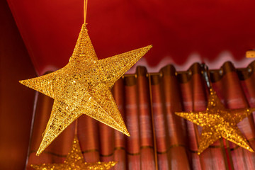 A large golden star hangs from a red ceiling.  Christmas ceiling decoration.