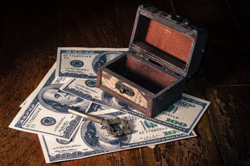 old metal key with small chest on money bills.