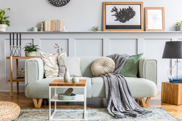 Stylish interior design of living room with modern mint sofa, wooden console, cube, coffee table, lamp, plant, mock up poster frame, pillows, plaid, decoration and elegant accessories in home decor.