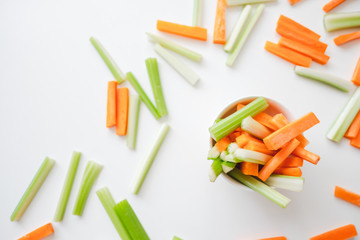 Sliced carrots and celery in a white bowl, healthy food background