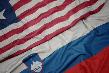 waving colorful flag of slovenia and national flag of liberia.