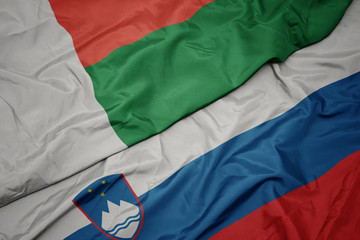 waving colorful flag of slovenia and national flag of madagascar.