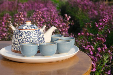 Tea set on table in flowers garden.