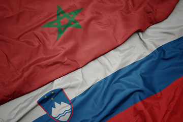 waving colorful flag of slovenia and national flag of morocco.