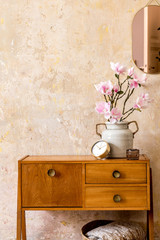 Retro composition of living room interior with wooden vintage commode, gold pink mirror, flower,...