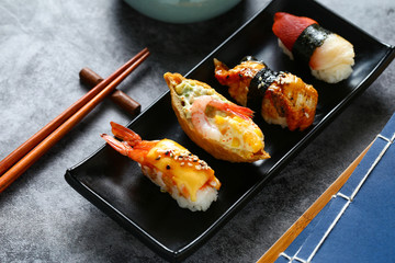 Japanese sushi in black plate on dark background