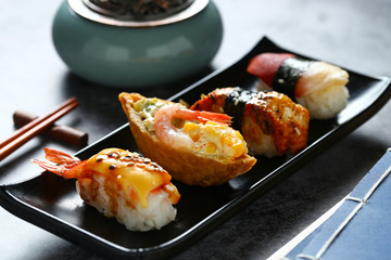 Japanese sushi in black plate on dark background
