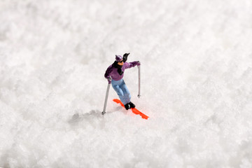 Lone miniature man skiing on fresh winter snow