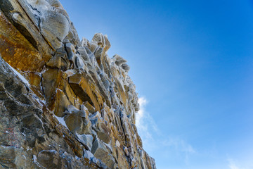 Wall of rock in snow amid blue sky