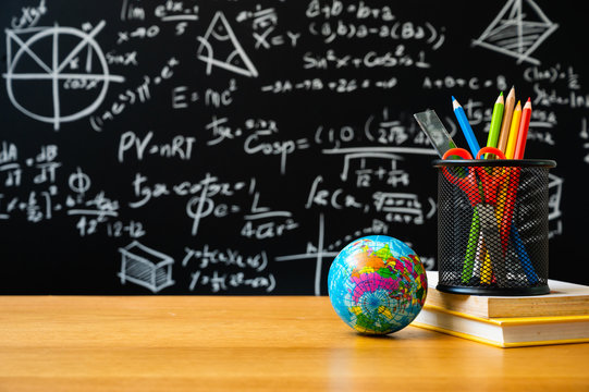 Education background concept. Stationery in holder color pencil, compasses tool, scissors, rulers, sharpener, globe On chalkboard with the Mathematical formula background.