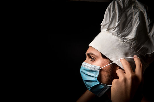 chef wears health mask due to coronavirus emergency called covid 19 on a black background 
