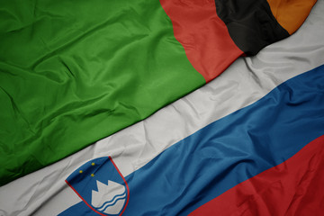 waving colorful flag of slovenia and national flag of zambia.