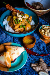 Indisches Curry-Reis-Gericht mit Erbsen und Blumenkohl dazu Samosas
