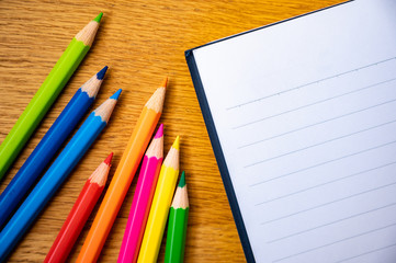 Fototapeta premium Education background concept. Color pencil on the wooden table with note book.