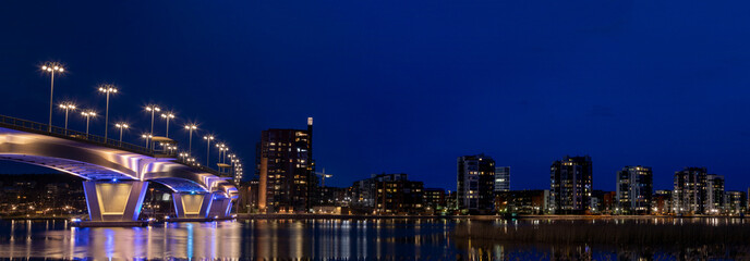 Illuminated bridge and city skyline with still water reflections in Finland