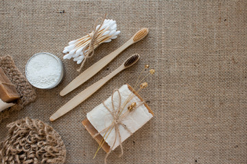 Fototapeta na wymiar Set of natural bathroom and home spa tools. Zero waste. Ecotolls toothbrushes, bamboo swabs, soap, dry shampoo, toothpowder, jute washcloth on fabric background with copyspace