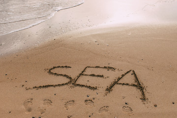 summer beach with sea lettering on sand