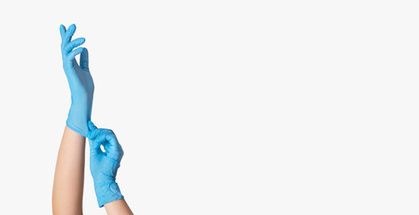 Young female putting on protective rubber gloves, closeup of hands. White background, isolated. Empty space
