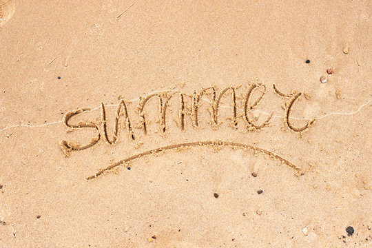 Hand written typography lettering Summer on golden sand. Drawing in sand for Happy Vacation, tourist Day, advertising, Summer inspirational quote. Romantic vacation, summer concept.
