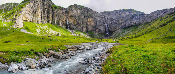 Dramatic panoramic view of creek and waterfalls in the swiss alps at Klausenpass at Canton Uri in Switzerland (vertical)